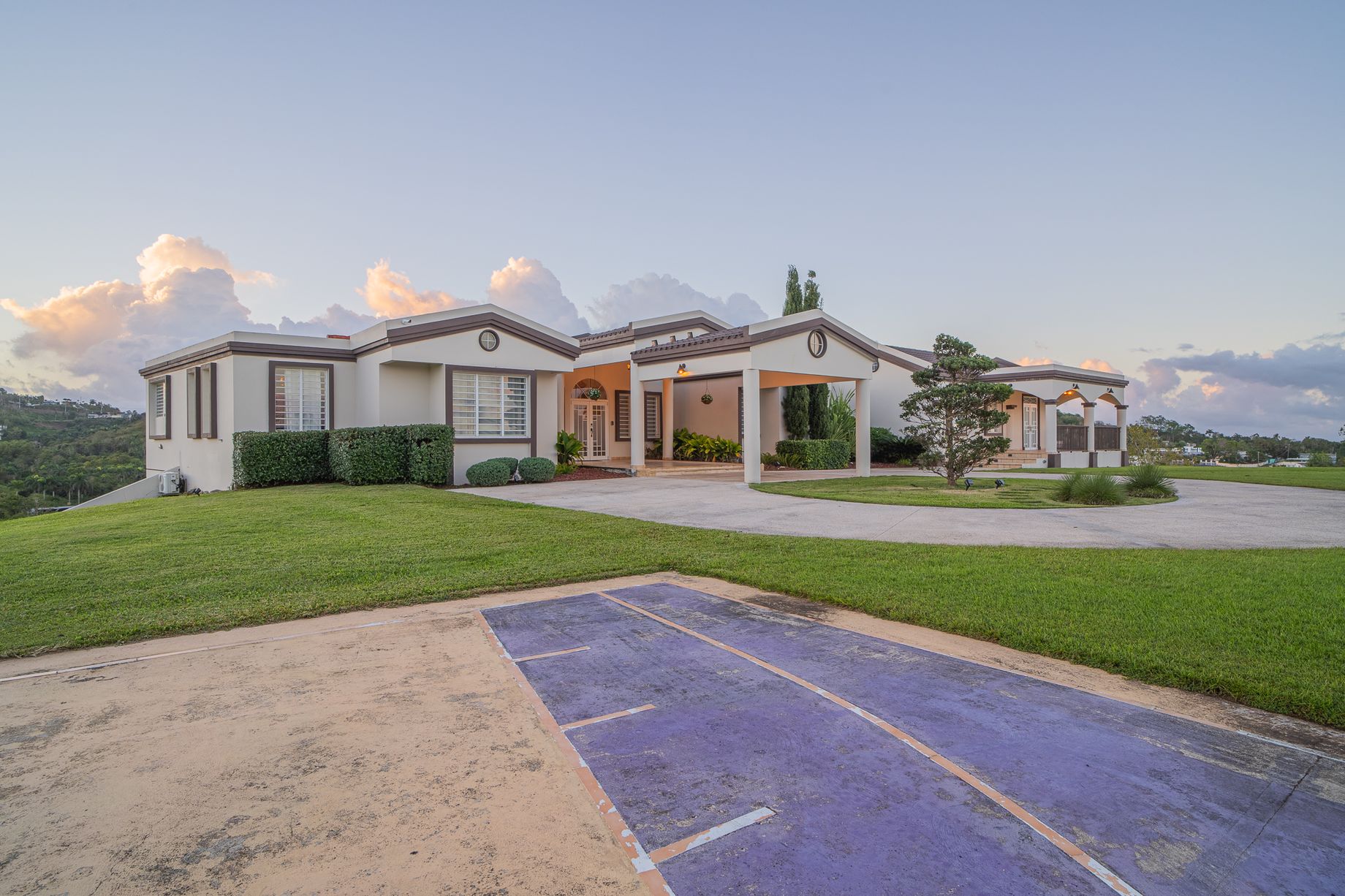 The two homes of Hacienda Santa Fe facing each other across the basketball court and wide central lawn at sunset