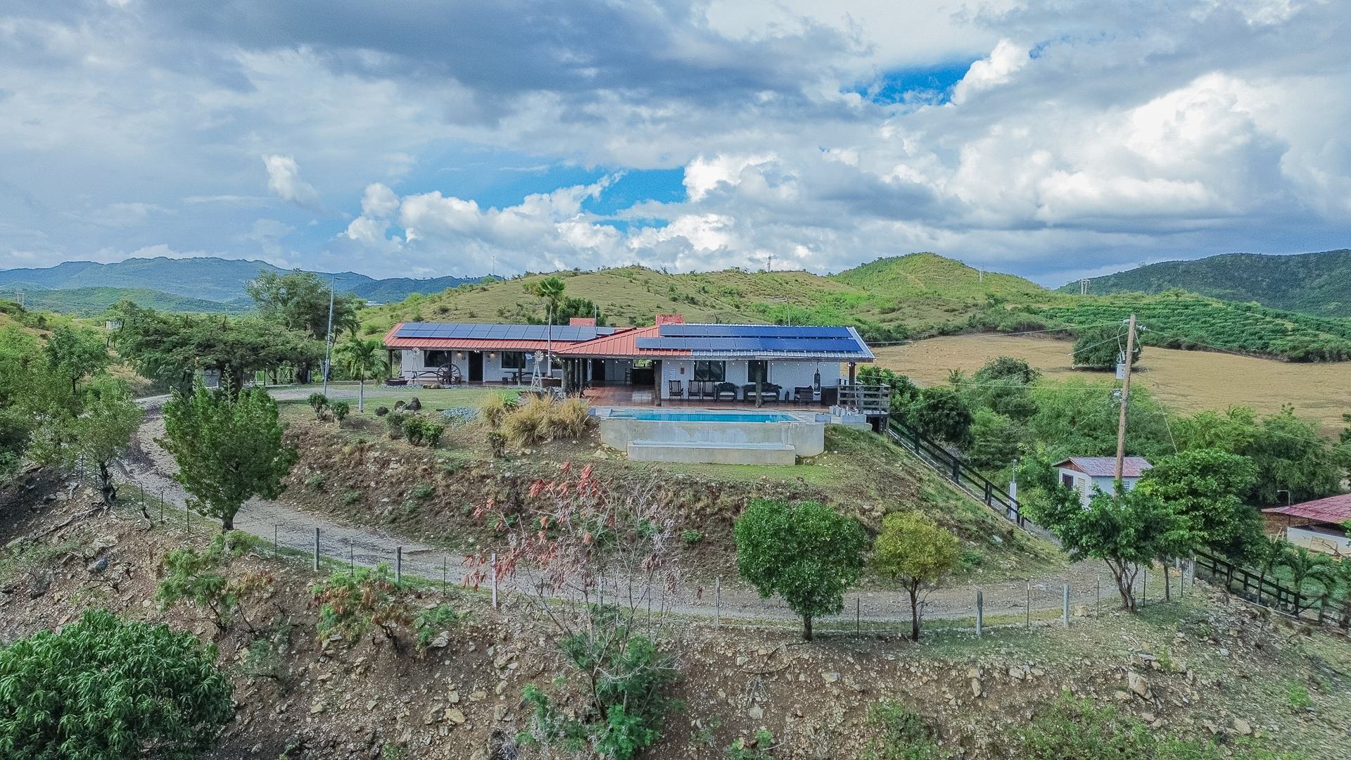 The property seen from the air across the valley, the house and pool sitting on a ridge below a line of mountains