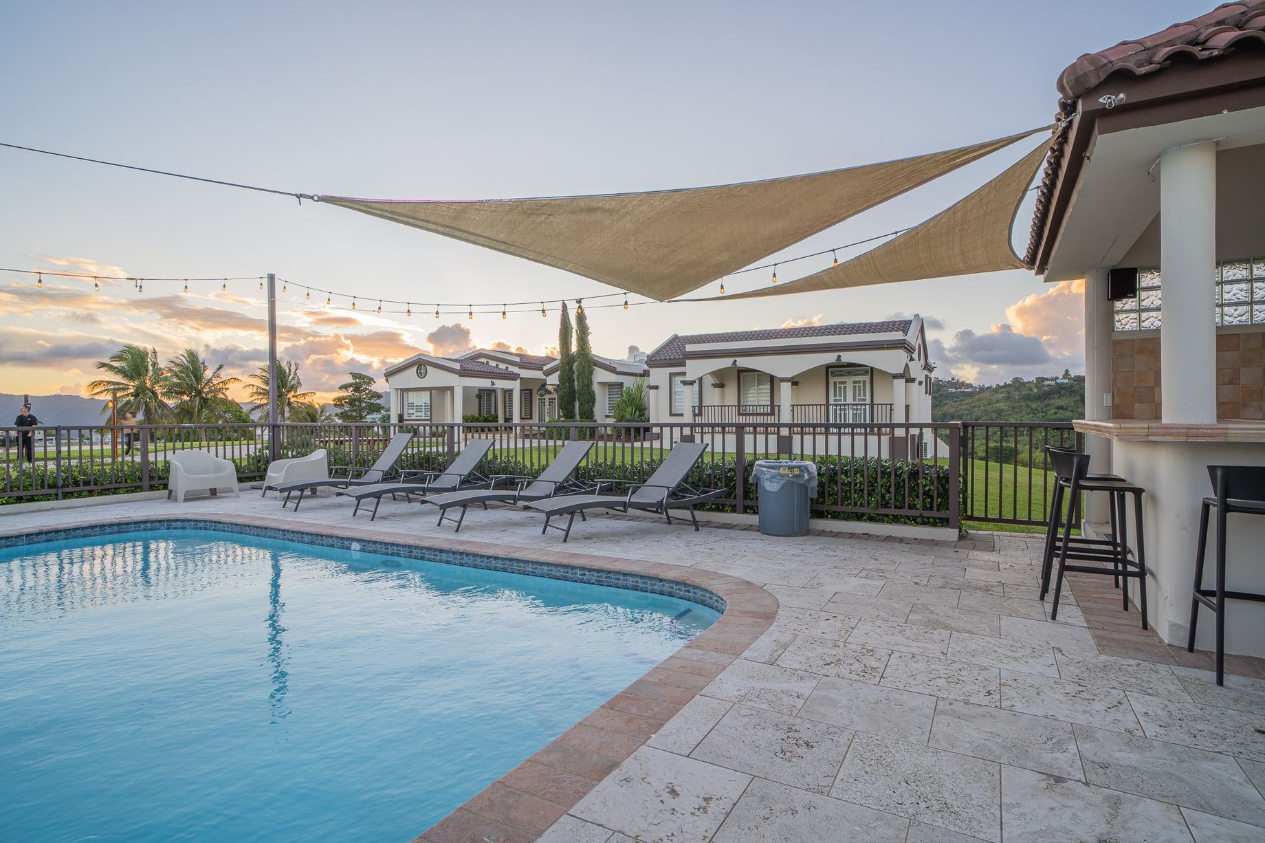 Swimming pool, shaded dining terrace and sun loungers with both houses visible across the grounds