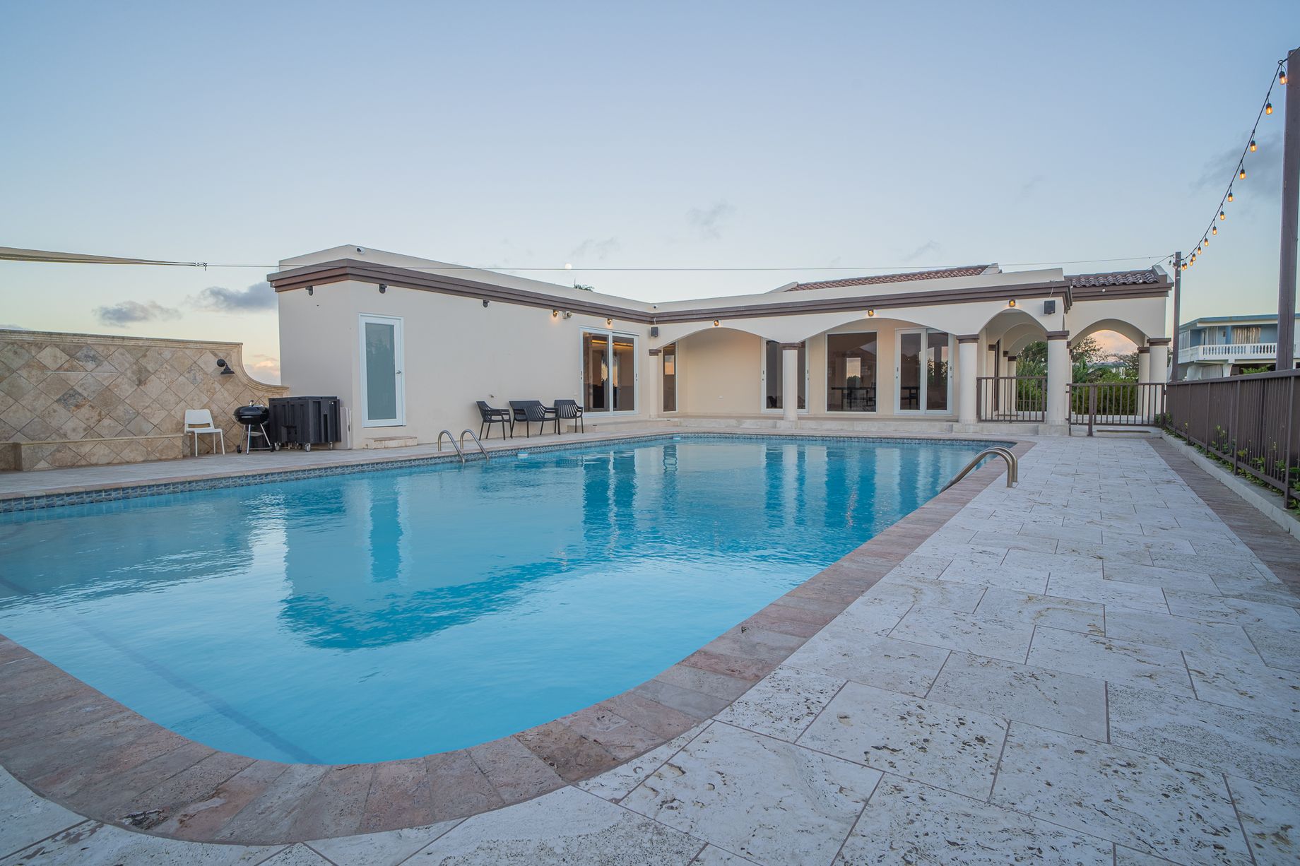 Wide pool terrace with the long swimming pool running between the guest house and covered gathering pavilion